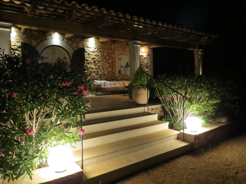 The lit stone steps up to the terrace at night, oleander in flower and a glowing globe lamp on either side